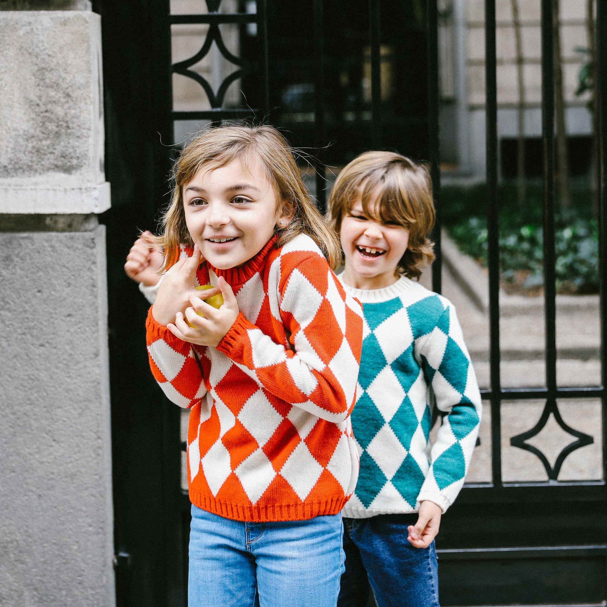 Niños riendo con jersey de rombos naranja y rombos verde